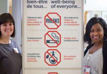Deux femmes aux côtés du panneau rappelant que le port de produits parfumés est interdit dans l'hôpital.