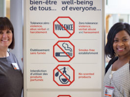Deux femmes aux côtés du panneau rappelant que le port de produits parfumés est interdit dans l'hôpital.