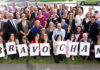Groupe de gens posant avec des affiches sur lesquelles on peut lire « Bravo CHAMP ».