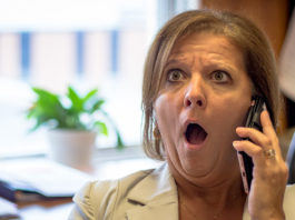 Femme surprise en parlant au téléphone.