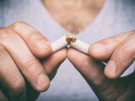 Plan rapproché des doigts qui casse une cigarette en deux.
