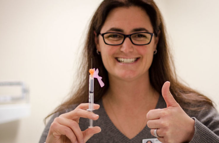 Femme tenant fièrement une seringue.