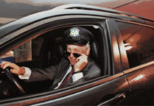 Dr Leduc déguisé en chauffeur de limousine, le logo d'Agrément sur sa casquette. Il a baissé ses lunettes de soleil et fait un clin d'oeil.
