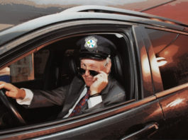 Dr Leduc déguisé en chauffeur de limousine, le logo d'Agrément sur sa casquette. Il a baissé ses lunettes de soleil et fait un clin d'oeil.
