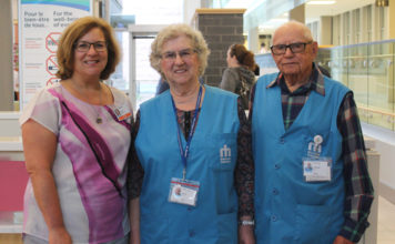 Trois adultes dans l'entrée principale de l'hôpital qui sourient