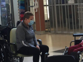 Une dame avec un masque assise sur une chaise