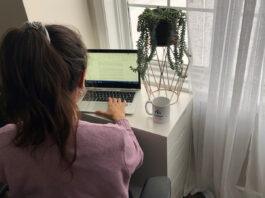 Femme qui tape à son ordinateur portable devant une fenêtre