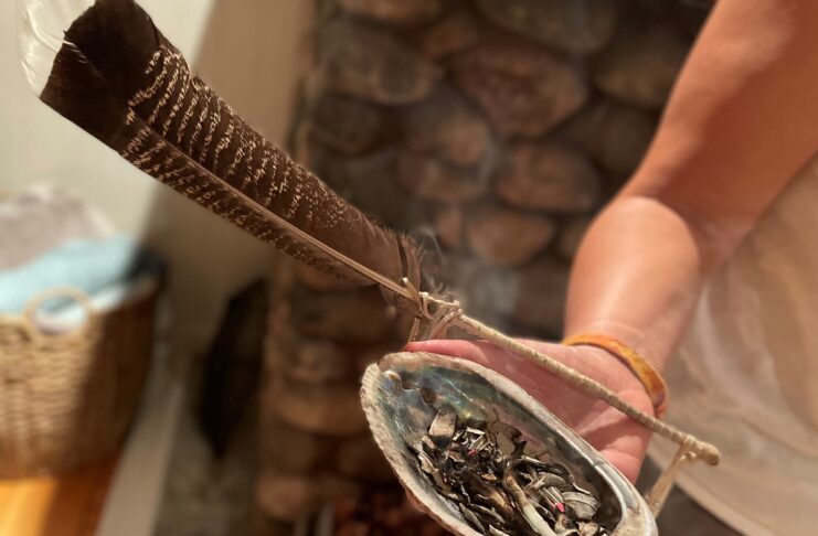 Un pas de plus vers la vérité et la réconciliation Main tenant une plume et un coquillage dans lequel brûle de la sauge sacrée