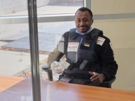 Agent de sécurité assis à un bureau, souriant