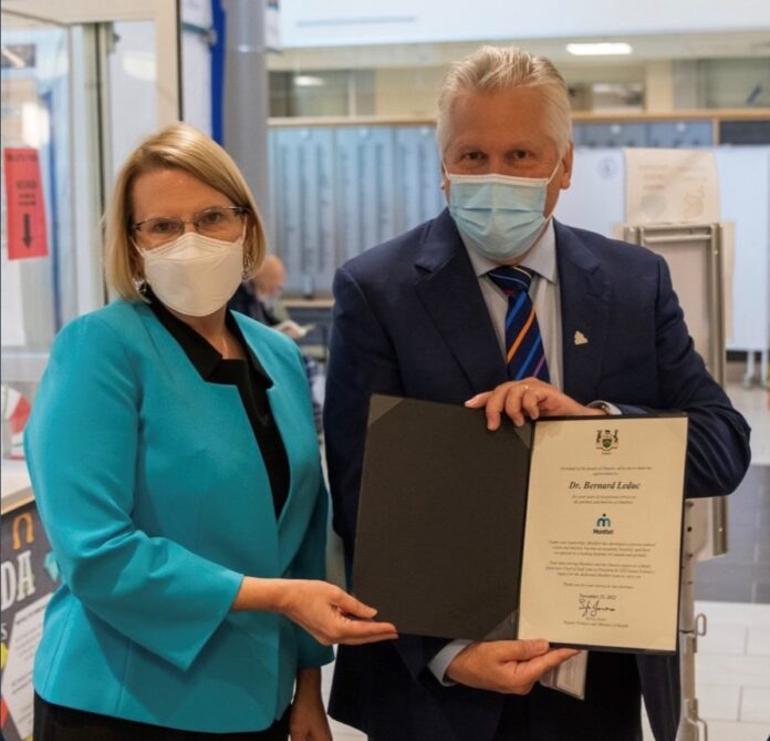 Sylvia Jones et Dr Leduc Une femme et un homme masqués sont côte à cote; l'homme tient un document officiel entre ses mains