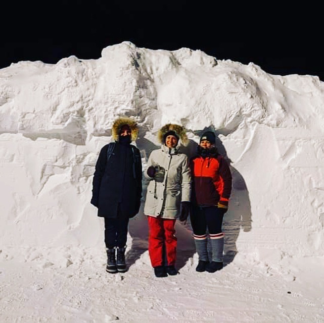 Trois personnes vêtues chaudement, devant un banc de neige plus haut qu'elles