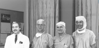 Photo d'archive en noir et blanc, quatre chirurgiens vêtus pour entrer à la salle d'opération