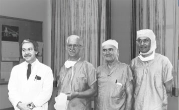 Photo d'archive en noir et blanc, quatre chirurgiens vêtus pour entrer à la salle d'opération