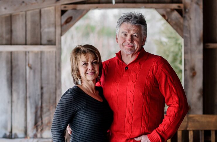 Photo d'une femme et d'un homme cinquantenaires souriants, dans une grange