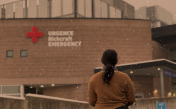 Femme en chandail brun devant une urgence avec de la neige