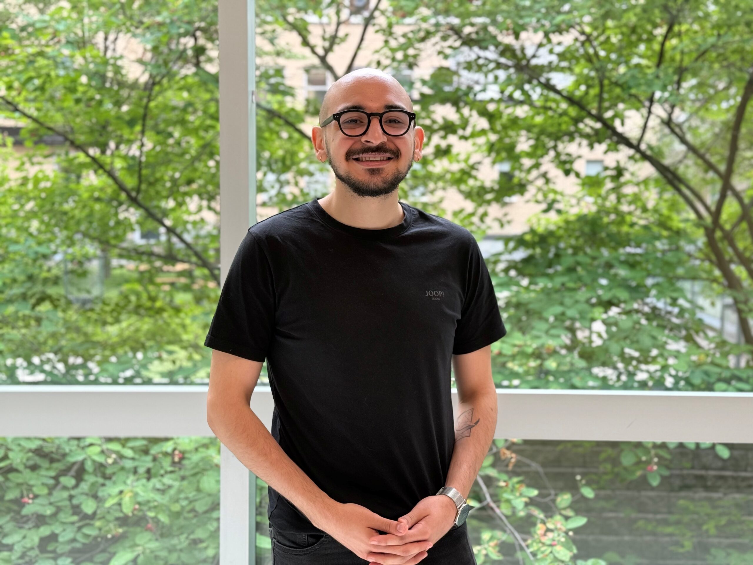 Homme debout devant une fenêtre souriant
